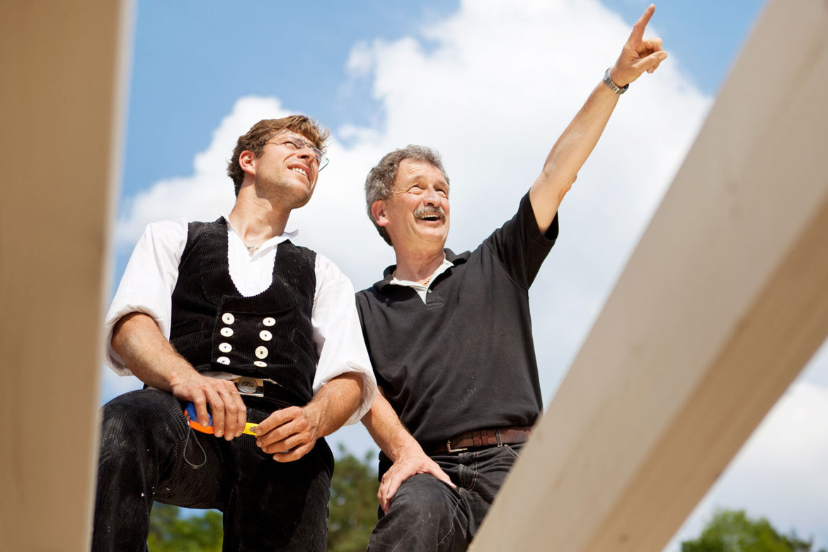 Close-up of two carpenters discussing the work on top of an unfinished roof